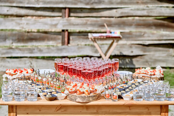 Buffet table with glasses of red champagne, glasses of water, canapes, sandwiches