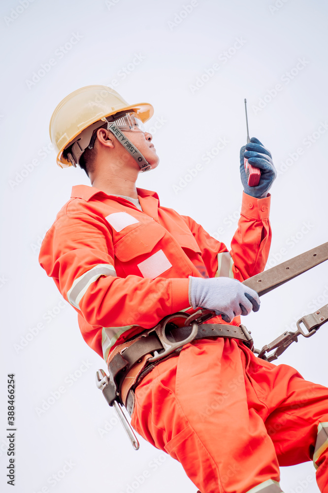 Poster an electrician in a safety suit is climbing a light pole to go up and check availability of the elec