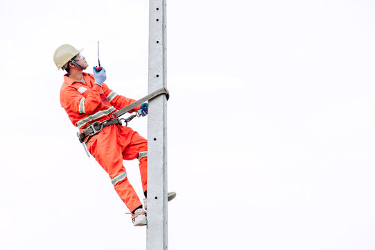 An electrician in a safety suit is climbing a light pole To go up and check availability Of the electrical system requesting a light pole sent to the public house