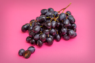 Top view bunch of ripe fresh black grape berry on pink surface