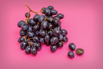 Top view bunch of ripe fresh black grape berry on pink surface