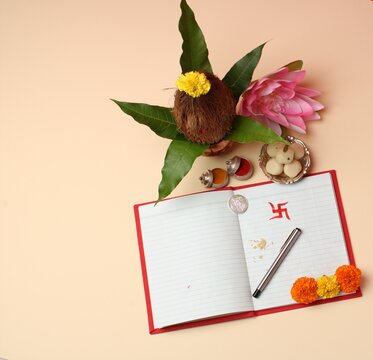Red accounting note book / bahi khata with copper kalash, sweets, marigold, haldi kumkum, pen with ink on Laxmi pujan, Diwali Festival