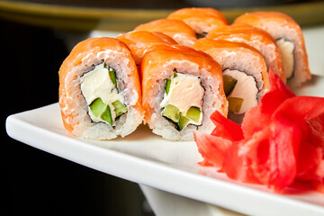 Rolls with salmon and cucumber, cheese and wasabi on a white plate. Closeup, selective focus