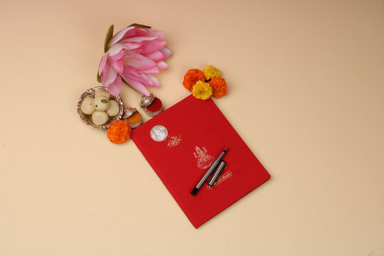 Red accounting note book / bahi khata with goddess Laxmi idol coin, diya, sweets, lotus, pen with ink on Laxmi pujan, Diwali Festival