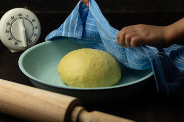 Proofing process of homemade bread dough on enamel ware, cover with blue napkin, with rolling pin...