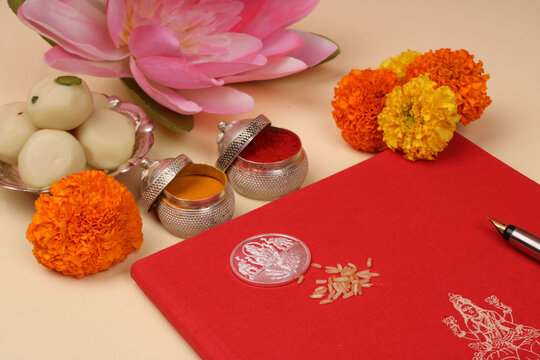 Red accounting note book / bahi khata with goddess Laxmi idol coin, diya, sweets, lotus, pen with ink on Laxmi pujan, Diwali Festival