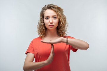 Pretty Young blonde woman doing time-out gesture with hands. Studio shot, white background. Facial...
