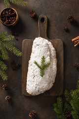 Christmas stollen - traditional German bread on brown background. Festive pastry dessert. View from above. Vertical format.