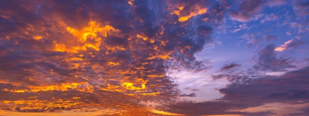 Fototapeta na wymiar Panorama Sunset with clouds, in orange and colorful shades,World Environment Day concept: Fiery orange sunset sky with dark clouds.