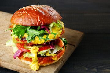 tasty burger with chicken and cheese on dark wooden background. Homemade hamburger or burger with fresh vegetables and cheese