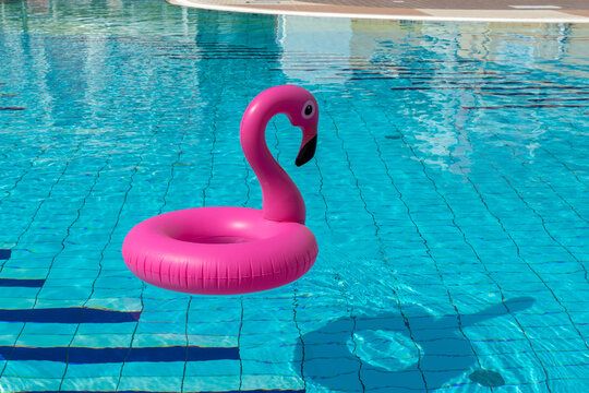 Sea background. Pink inflatable flamingo in pool water for summer beach background. Luxury lifestyle travel.