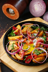 frying pan with potatoes meat and vegetables closeup with ingredients on background