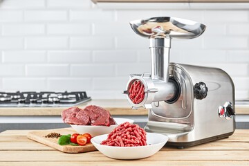 Bowl of mince with electric meat grinder in kitchen interior
