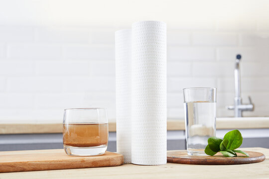 A Glass Of Clean And Dirty Water With Filter Cartridges On The Home Kitchen Background