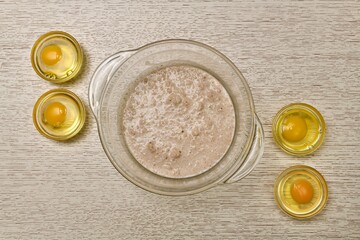 A bowl of fermented diluted yeast four round containers in each of the broken eggs.