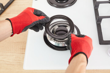 Worker install burner on gas hob in kitchen interior. Repairs of gas control panel.