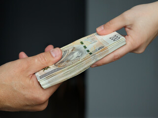 male hand giving a bundle of large banknotes to female hands. selective focus