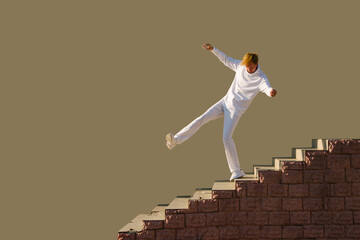 A young man dressed in white balances precariously on the edge of a staircase.