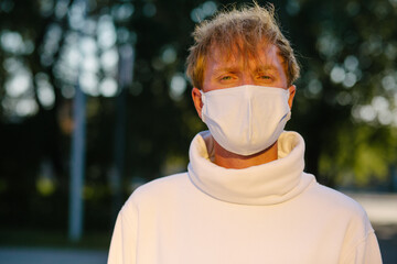 Portrait of a young man in a medical protective mask looking straight.