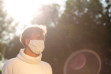 Portrait of a young man in a medical protective mask looking straight.