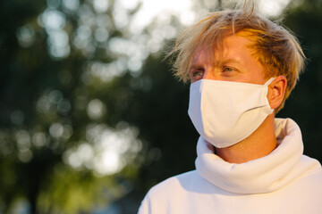 Portrait of a young man in a medical protective mask looking straight.