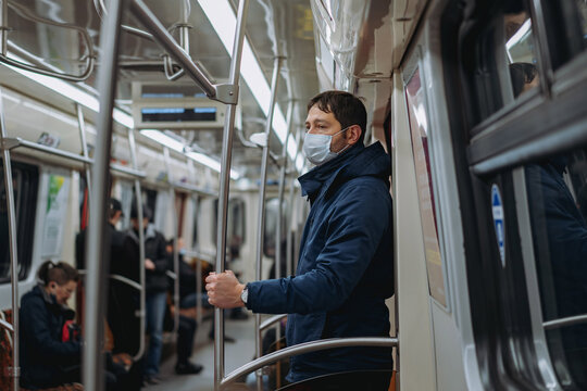 caucasian man wearing medicine mask traveling by tube, standing in subway car looking aside.Image with selective focus