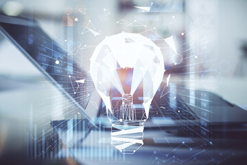 Computer on desktop in office with bulb icon hologram. Double exposure. Concept of idea.