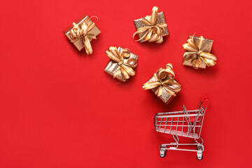 Golden gifts boxes and shopping cart on red background. Black friday sale and shopping day concept