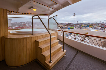 Outdoor jacuzzi whirlpool on the deck of a Norwegian cruise ship lying in port in Trondheim with city in background