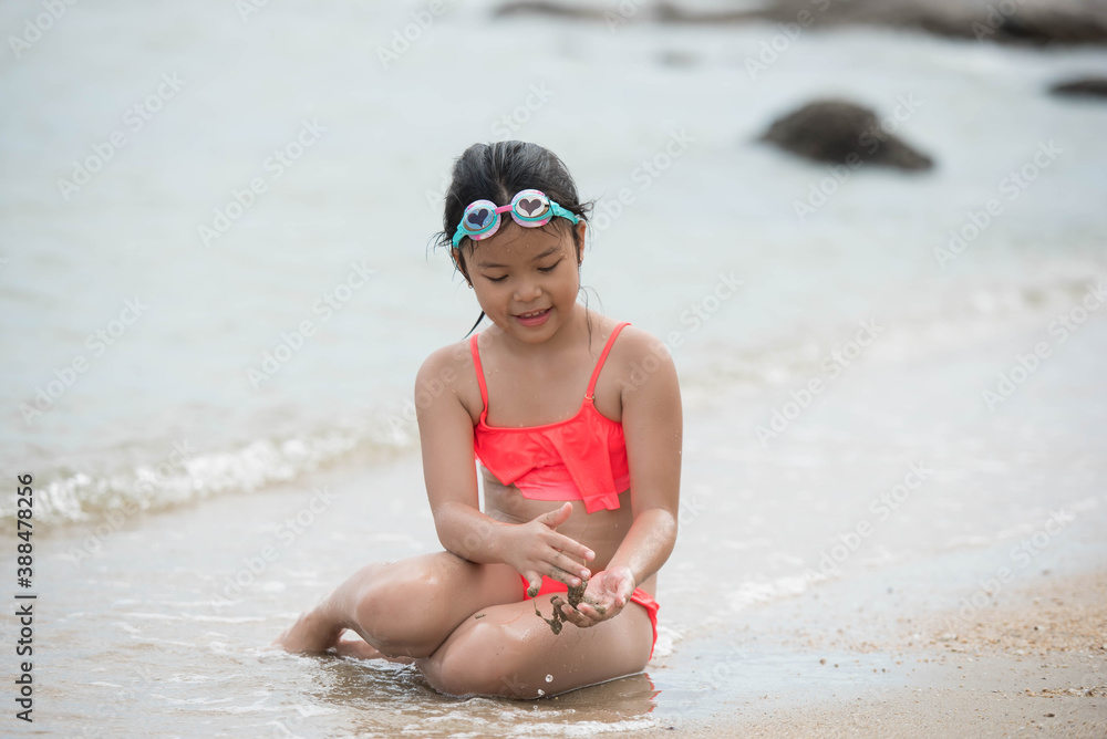 Wall mural child relaxing on the beach against sea and sky background. summer vacation and travel concept. happy child playing with sand at the beach in summer.