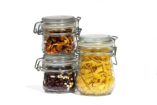 Assortment of raw grains, cereals and pasta in three glass jars on a white isolated background. The concept of zero waste. Close-up, selective focus