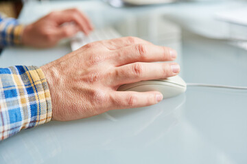 Hand von einem Senior bedient Computermaus
