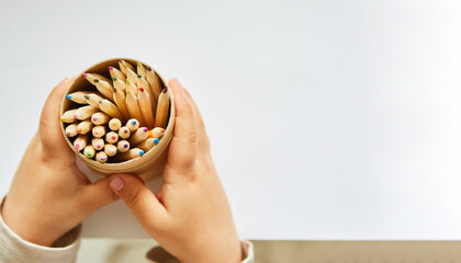 Hände von Kleinkind halten Becher mit Buntstiften
