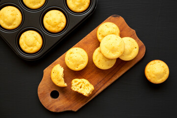 Homemade Cornbread Muffins on a rustic wooden board on a black surface, top view. Flat lay, overhead, from above.