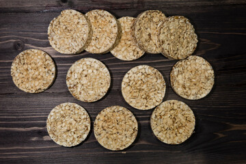 On a dark wooden background, there are pieces of round whole grain bread intended for weight loss.