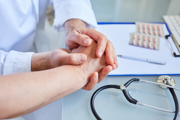 Ärztin hält die Hand von Patient in ihren Händen