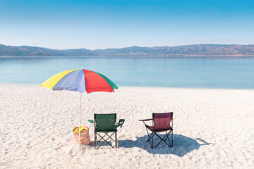 Two chairs and a parasol on the white sand beach on lake Salda. Turkish Maldives and relax in Paradise concept