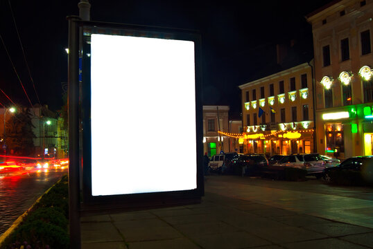 Blank signboard on the background of the night city. Mockup for design. Free space for advertising. Sharpness on the banner from the edge of the frame.