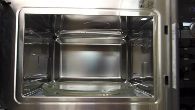 View inside of microwave oven, concept of cooking and technologies. Household utensils. Close up of empty microwave turntable glass tray inside of the microwave oven.