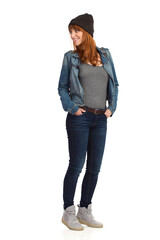 Cheerful Young Woman In Jeans Jacket And Winter Cap Is Looking Away Over The Shoulder