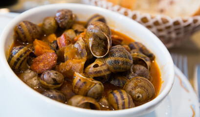 Appetizer of snails stewed to homemade with chorizo served in white bowl..
