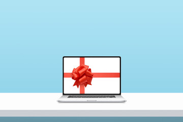 Laptop with ribbon and bow on display. Minimal concept of Christmas shopping