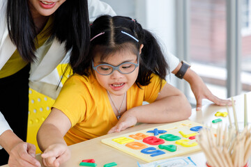 Girl with Down's syndrome play puzzle toy with her teacher.