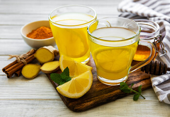 Energy tonic drink with turmeric, ginger, lemon and honey on a white wooden background