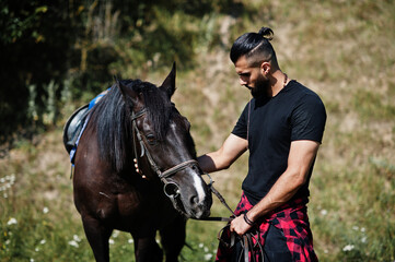 Obraz premium Arab tall beard man wear in black with arabian horse.