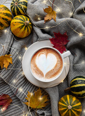 Cup of coffee, dry leaves and scarf on a table
