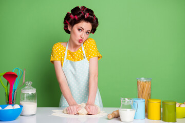 Photo of beautiful girl prepare homemade cake knead raw fresh dough make lips pouted wear yellow dotted t-shirt hair rollers isolated over green color background