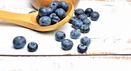Blueberries on white wooden tables and rustic wooden utensil, spoon