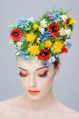Closeup beauty portrait. Beautiful girl with spring colorful flowers. Beauty Face. Creative Make up and Hair Style.