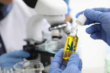 Chemical scientists examine composition of hemp extract under microscope in chemical laboratory...